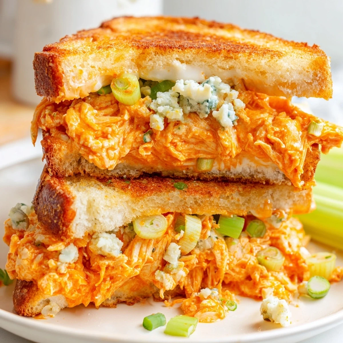 Close-up of a generously filled Buffalo Chicken Grilled Cheese oozing melted cheese and buffalo chicken.