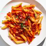 A close-up of delicious Penne all'Arrabbiata, showcasing the fiery red sauce and perfectly cooked penne.