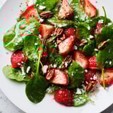 A closeup reveals components of the Spinach Strawberry Salad with a sweet poppy seed dressing.