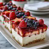 Festive Fourth of July No-Bake Cheesecake Flag Cake with fresh blueberries and strawberries arranged in patriotic stripes.