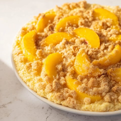 A warm, golden Rustic Peach and Almond Tart, with visible juicy peaches atop a buttery filling.