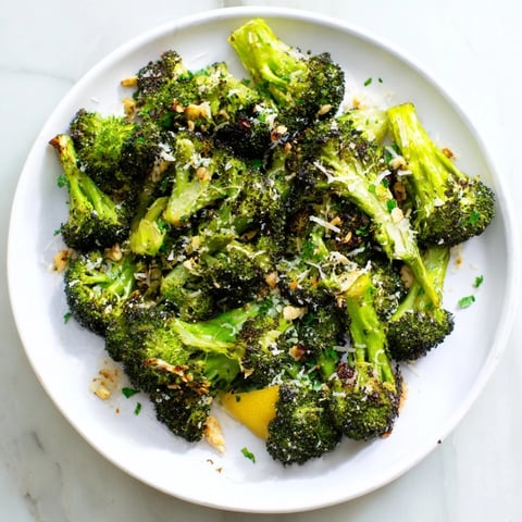 Vibrant image: golden Simple Garlic and Parmesan Roasted Broccoli sprinkled with fresh parsley and lemon zest.