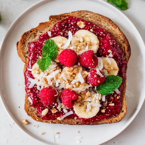 Warm, golden toast generously spread with bright raspberry chia jam, a sweet and delicious breakfast.