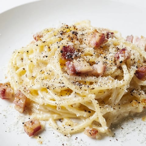 A steaming bowl of Express Spaghetti Carbonara: Creamy pasta coated in rich sauce with crispy bacon.