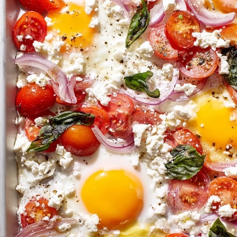 Bright sheet pan of Tomato Feta Baked Eggs, ready to eat alongside crusty bread.