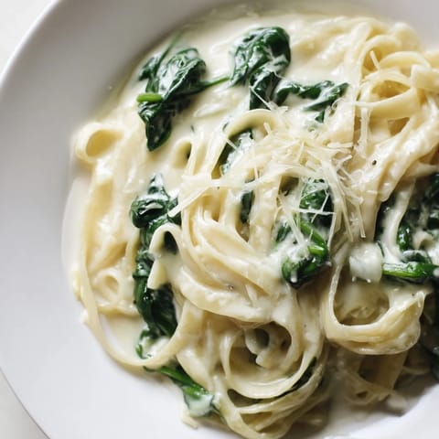 Steaming bowl of Creamy Garlic Spinach Pasta garnished with fresh parsley, ready for a comforting vegetarian dinner.  