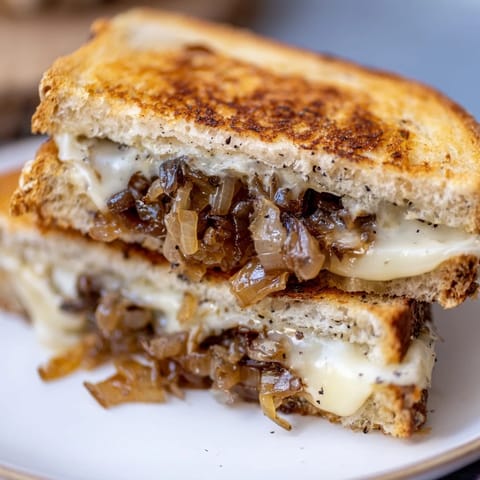 Thick, crispy bread layered with tender caramelized onions and gooey Caramelized Onion Grilled Cheese on a rustic cutting board.
