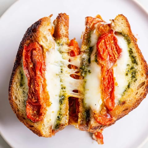 The crispy crust of Roasted Tomato Pesto Grilled Cheese reveals layers of caramelized tomatoes and fresh basil pesto.