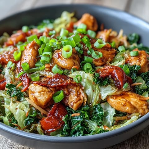 A close-up of Chicken Cabbage Stir-Fry featuring colorful carrots and red bell peppers tossed with juicy chicken pieces on a skillet.