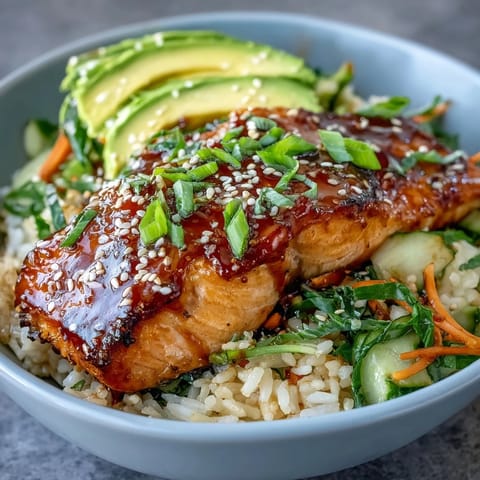 Fresh teriyaki-glazed salmon fillet served over steaming jasmine rice with crisp cucumber and avocado slices.