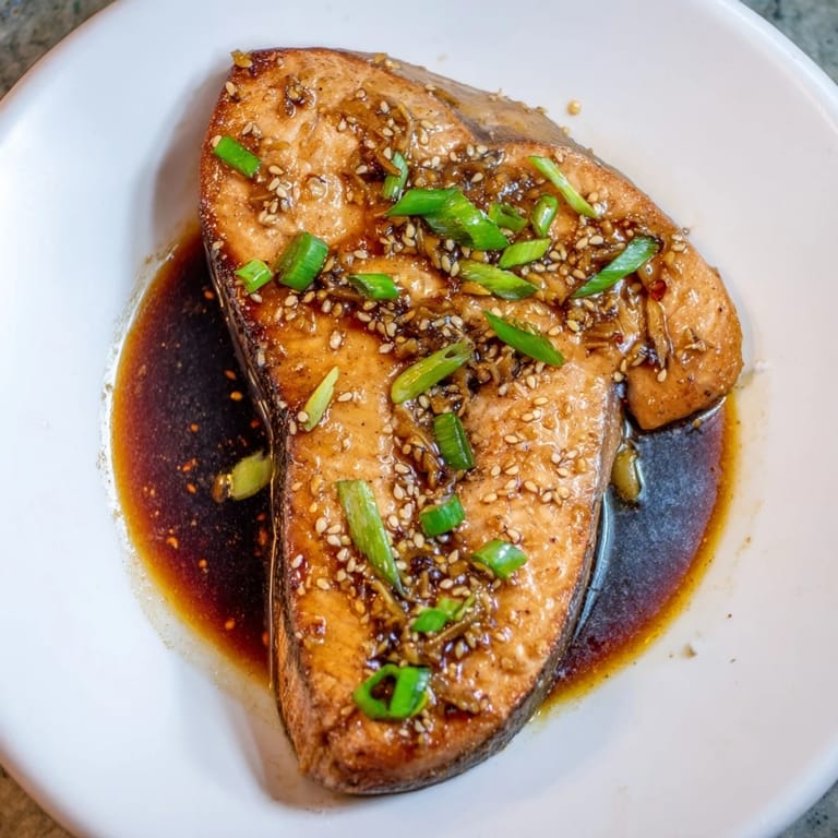 Beautifully cooked Ginger Soy Glazed Salmon showing off its tender flaky texture, garnished with sesame seeds and green onions.