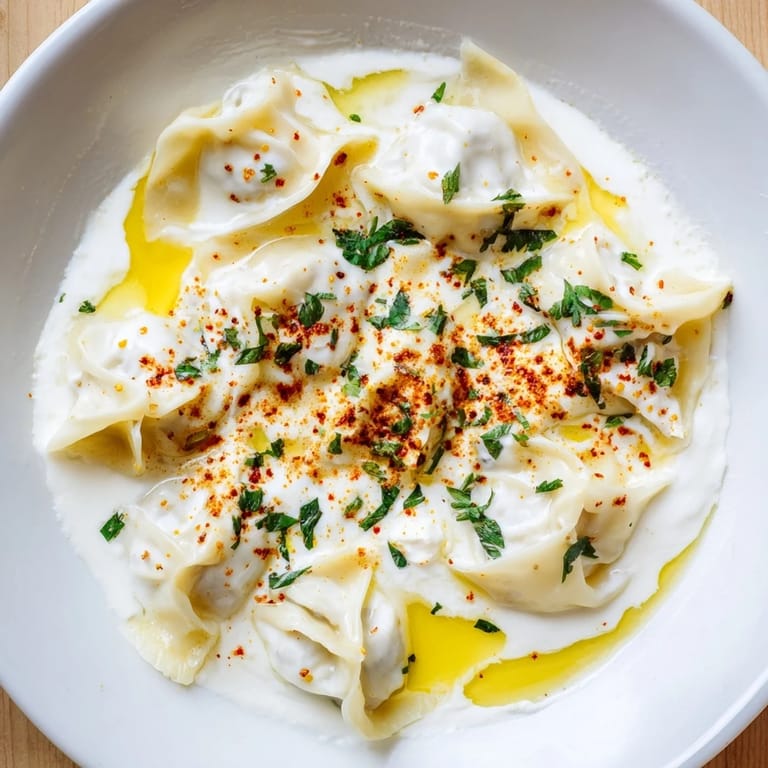 Flavorful Turkish cheesy manti served, featuring tender dumplings and a cool, creamy yogurt topping.