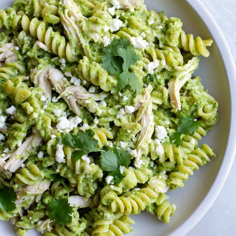 Cilantro Lime Chicken Pasta served in a white bowl with crumbled feta cheese and fresh lime wedges.
